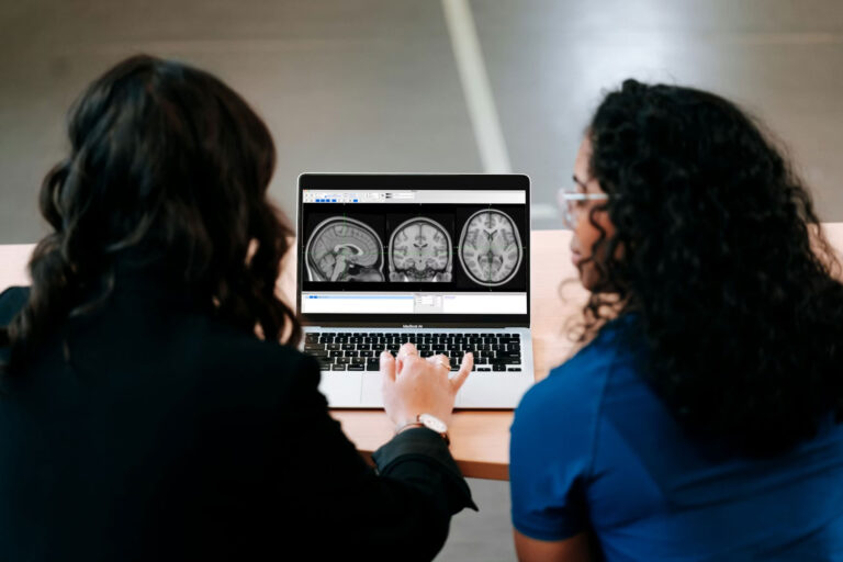 Two-women-looking-at-a-computer-screen-with-mri-images-on-it