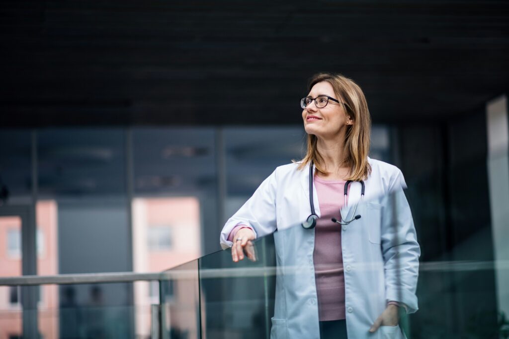 A woman doctor looks outward from the terrace of a hospital.