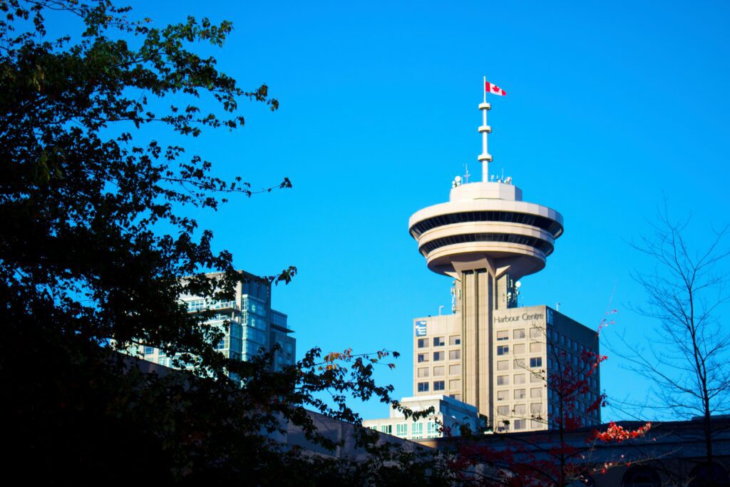 Vancouver's Harbour Centre and the waving Canadian flag on top with a blue sky behind it.