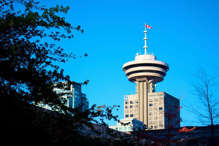 Vancouver's Harbour Centre and the waving Canadian flag on top with a blue sky behind it.